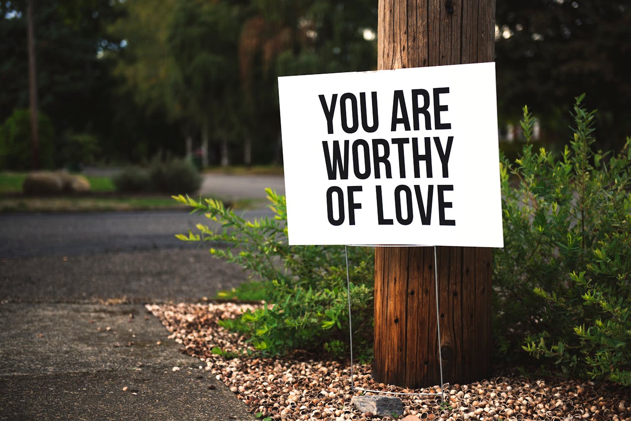 services-02 A positive message sign u0022You are worthy of loveu0022 in a park setting.